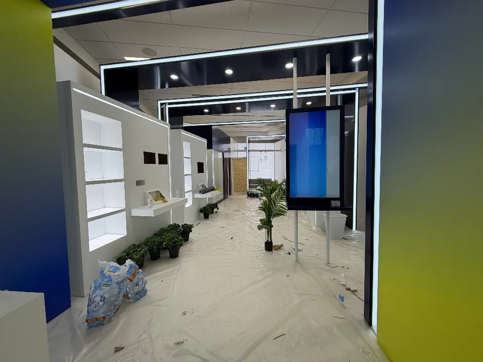 Corridor of lit portal frames with white product niche walls, planters and a hanging screen