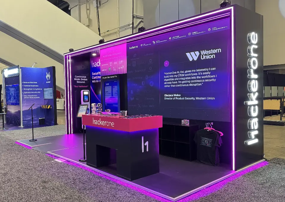 HackerOne pink-topped counter in front of a backlit wall carrying a Western Union customer quote