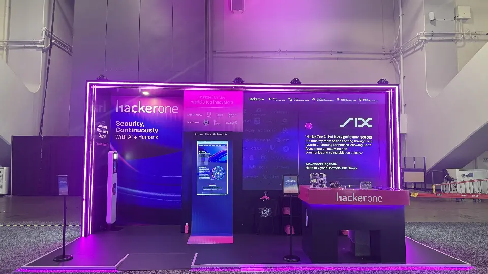 Front view of the HackerOne booth at RSAC 2026 with magenta-lit black frame and backlit wall