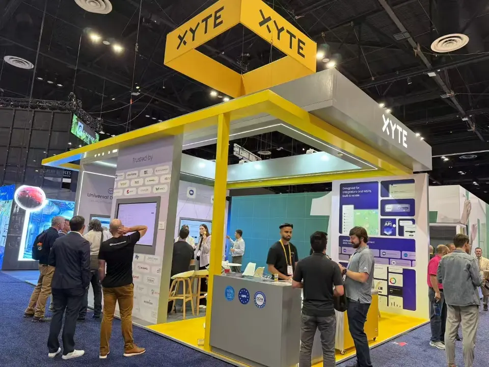 XYTE booth with yellow square hanging sign, Trusted by logo wall and grey counter