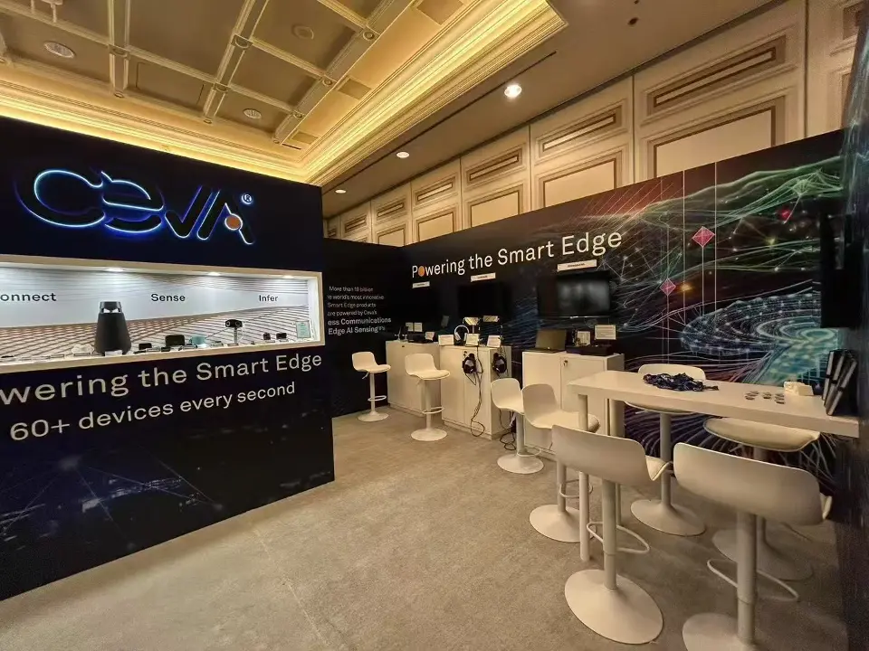 Ceva CES 2025 suite with glowing logo, lit product window and white high-top meeting tables