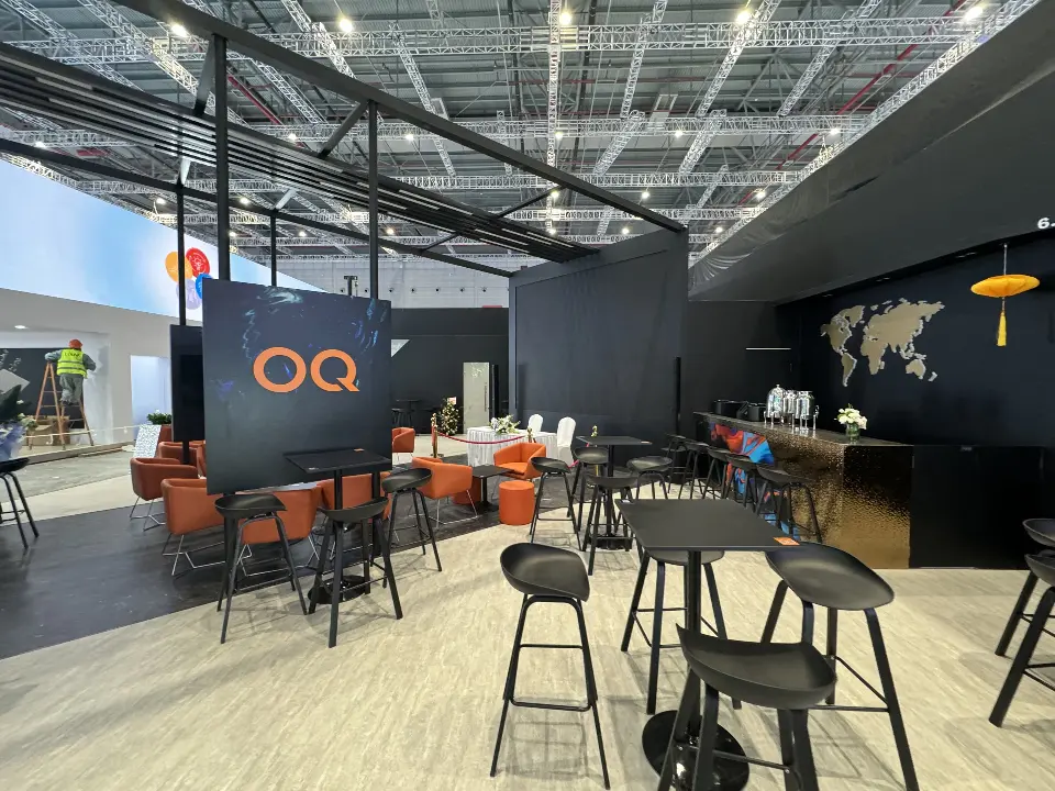 Black high tables and stools in the open seating area with OQ wall graphic