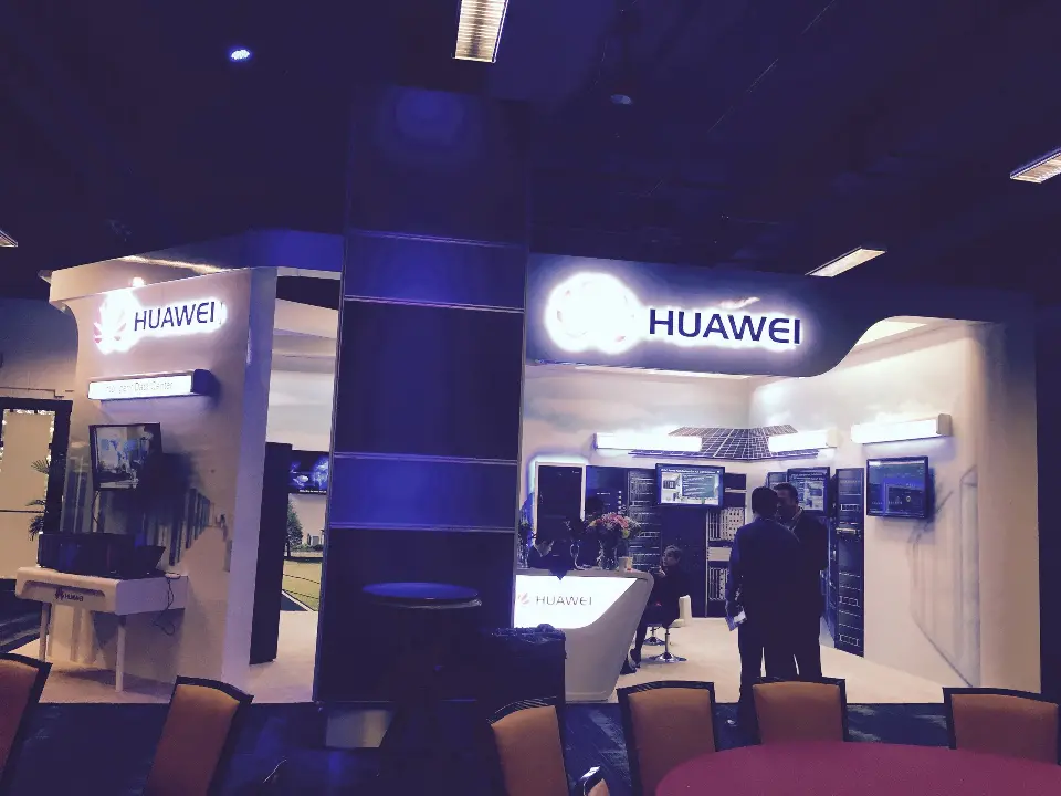 Front corner of the booth with lit logo, white counter and blue-wrapped column