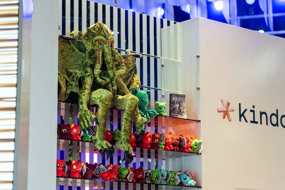 Close view of colourful plush creatures on the striped shelf wall by the kindo logo
