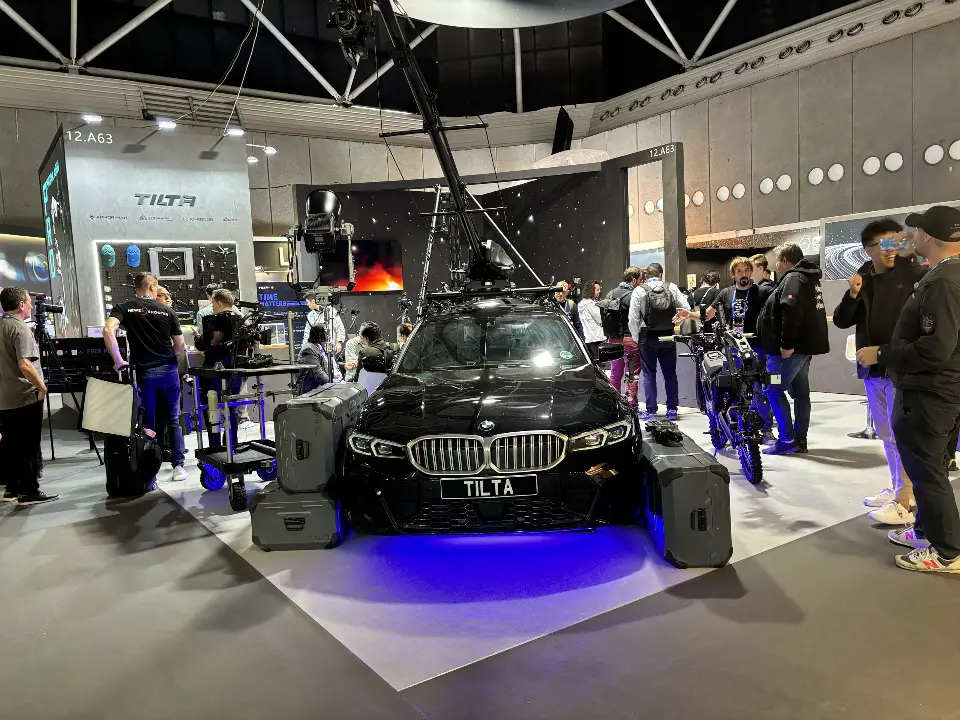 Front of the car with camera crane arm and visitors in the aisle