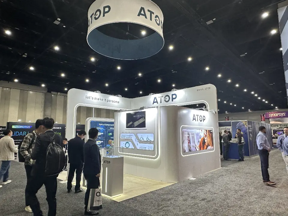 Wide view of the ATOP booth under the round hanging sign with visitors in the aisle