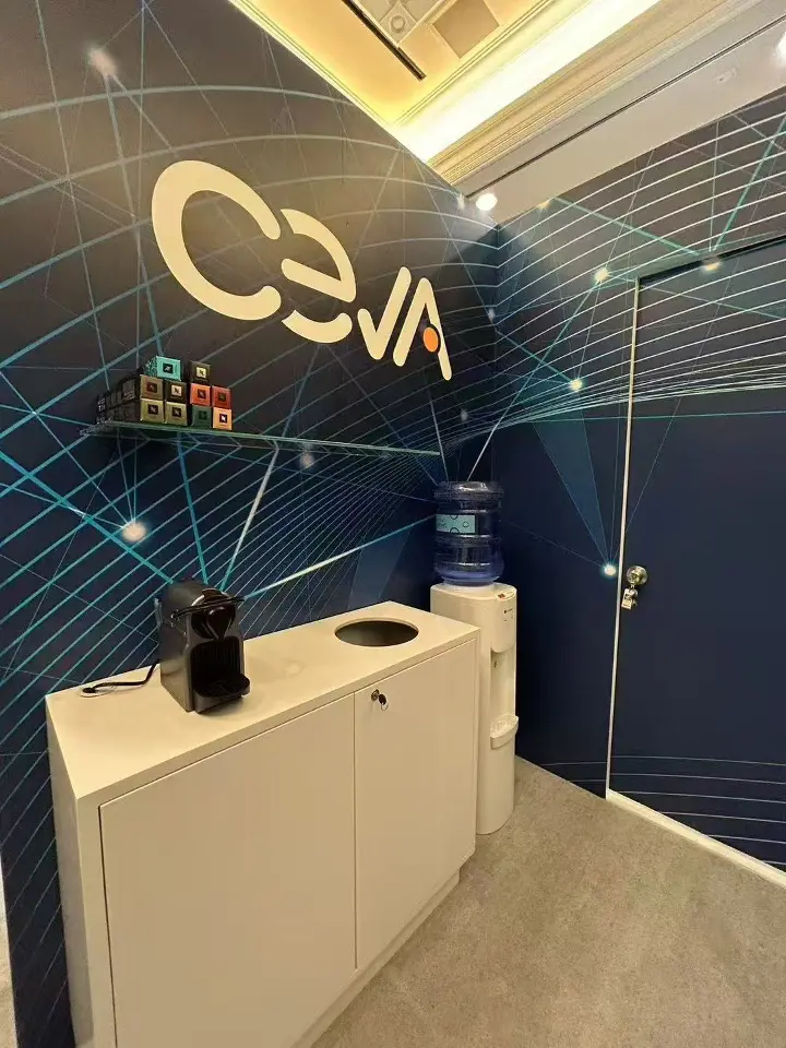 Navy wall with the Ceva logo above a white cabinet with a coffee machine