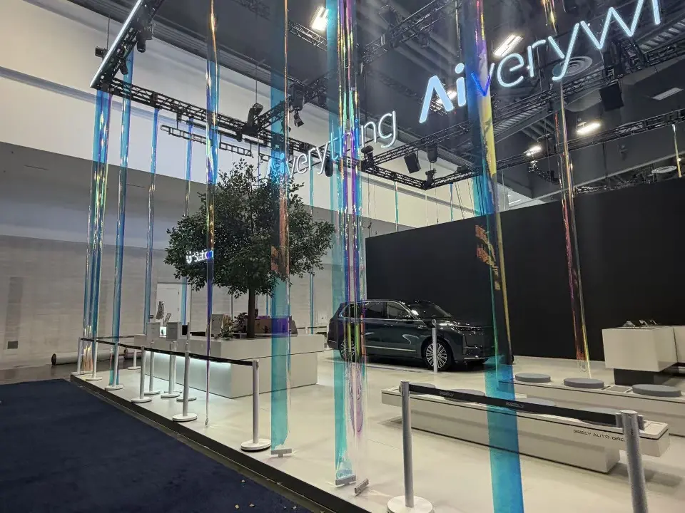 Iridescent hanging strands and a tree beside a car under Aiverything lettering