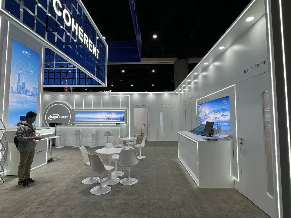 COHERENT side of the tower with white lit-frame walls and a presenter
