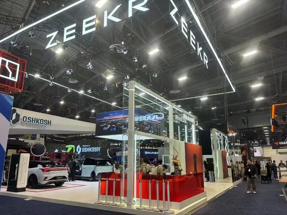ZEEKR glass-framed reception corner with a red counter and screen banner beneath the illuminated ZEEKR lettering