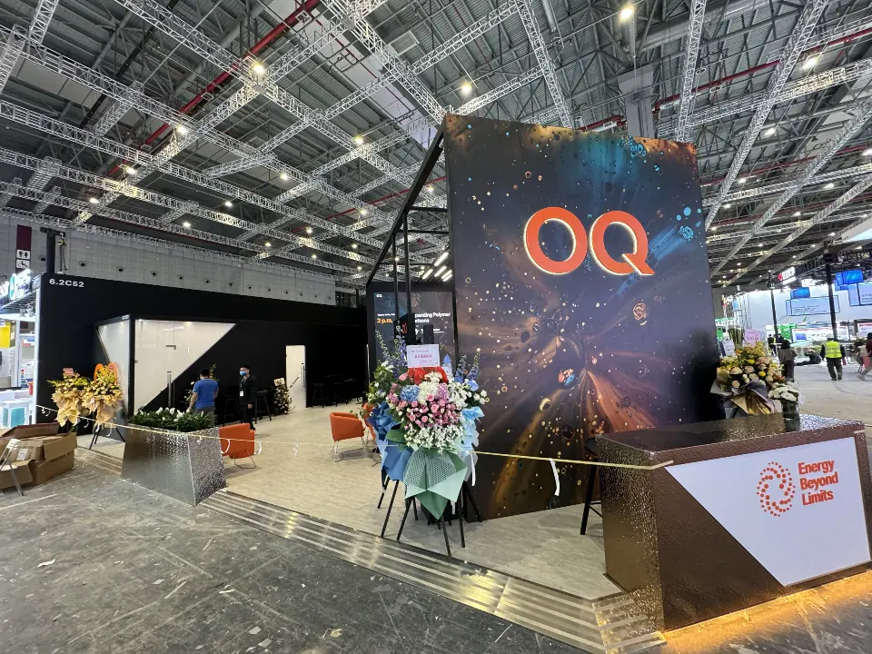 Front of the OQ tower with lit welcome counter and flower arrangements behind rope line