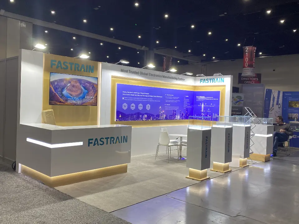 Counter view of the FASTRAIN booth with screen video and white showcases