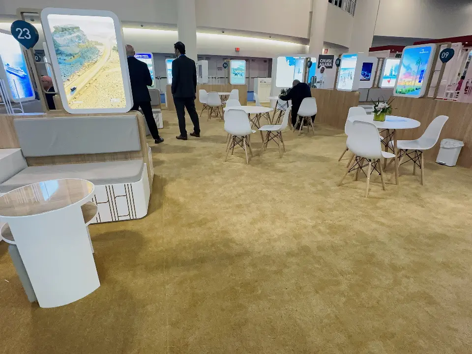 White meeting tables and chairs on beige carpet with backlit destination graphics