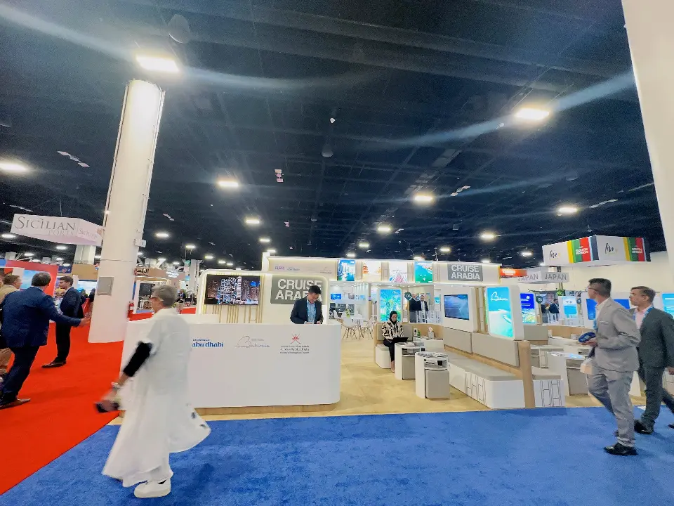 Visitors walking past white counters and meeting pods along the booth front