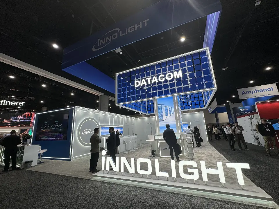Wide view with visitors, lit INNOLIGHT letters and the DATACOM grid tower