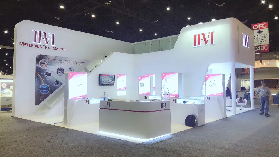 Front of the booth with II-VI logos, backlit panels and long white counter