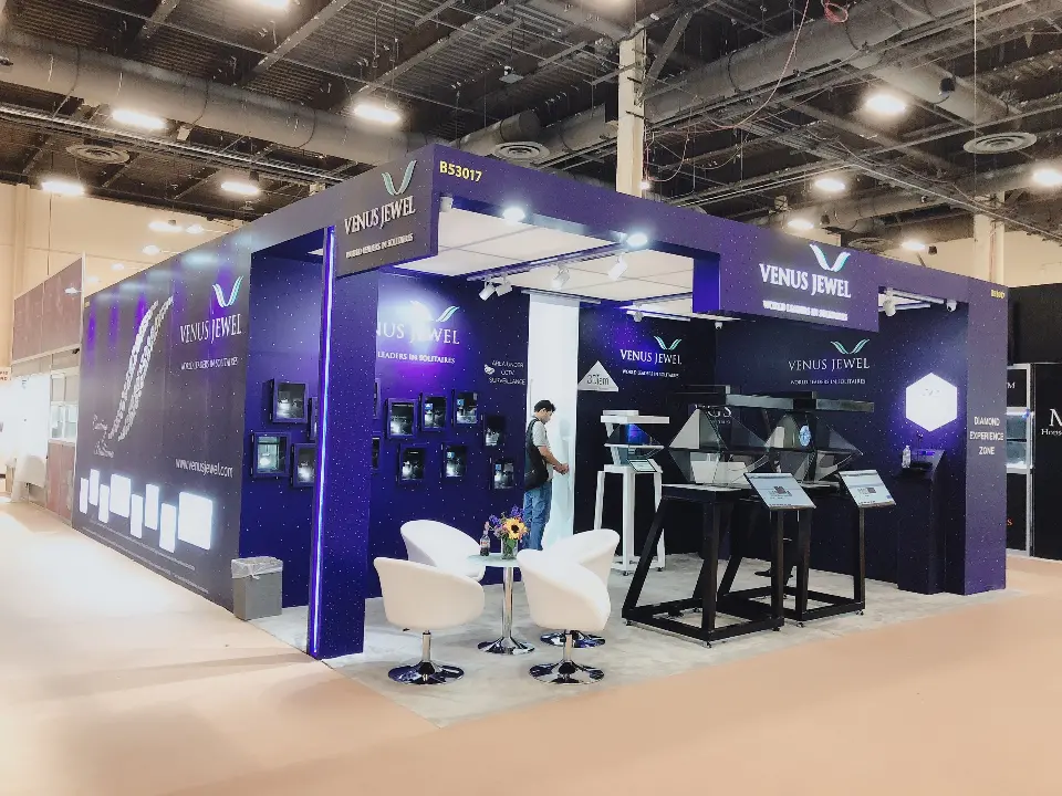 Corner view of Venus Jewel booth with white swivel chairs, lit niches and pyramid cases