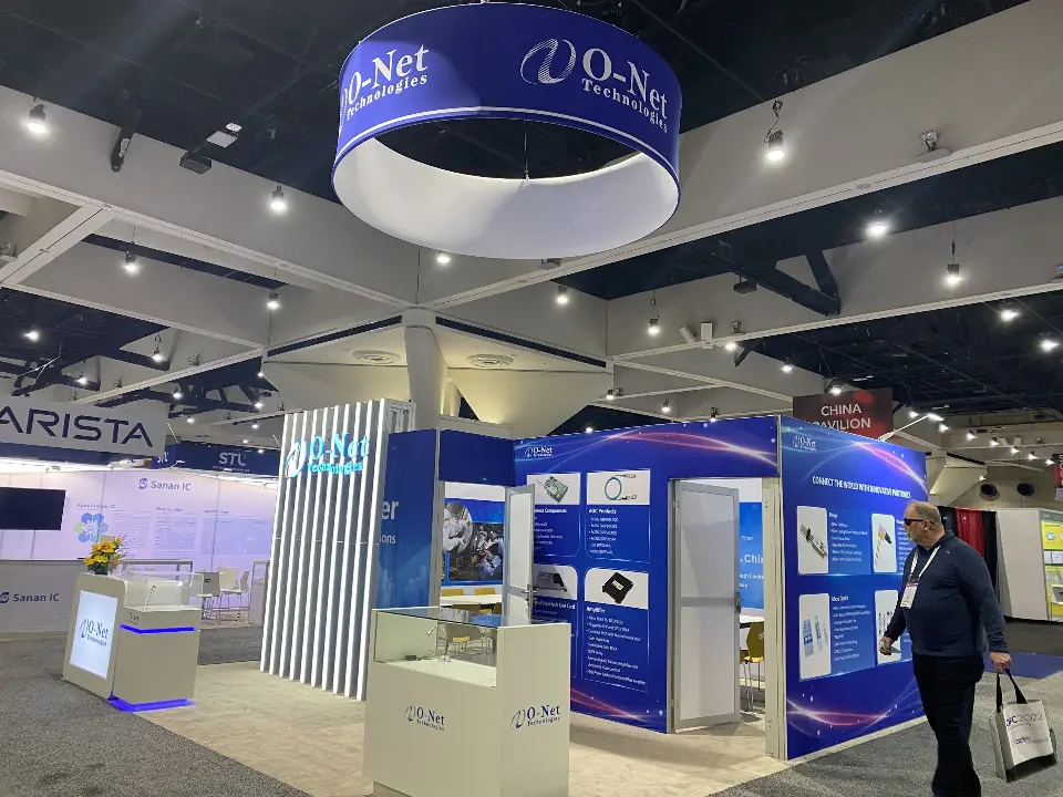 O-Net booth corner with white counters, display panels and lit slat wall under the ring sign