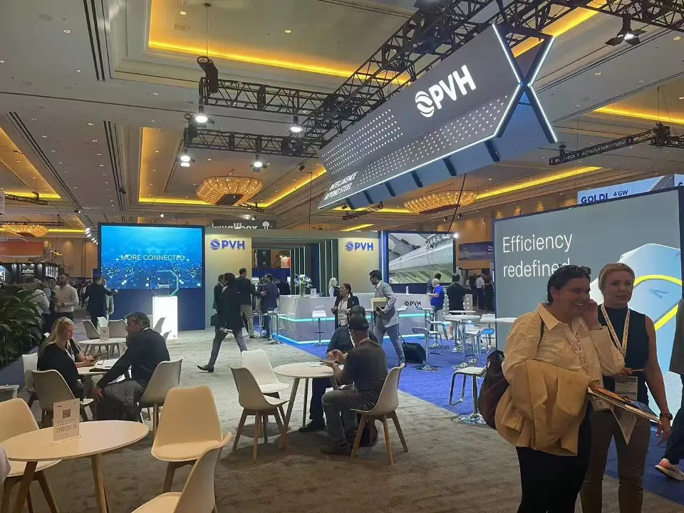 Meeting area of the PVH booth with round tables, white chairs and backlit graphics