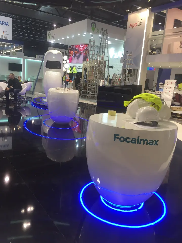 White pod display table with product samples set on a lit blue base ring