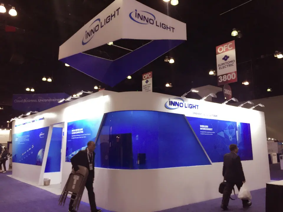 Visitors walking past the blue glass wall of the InnoLight booth