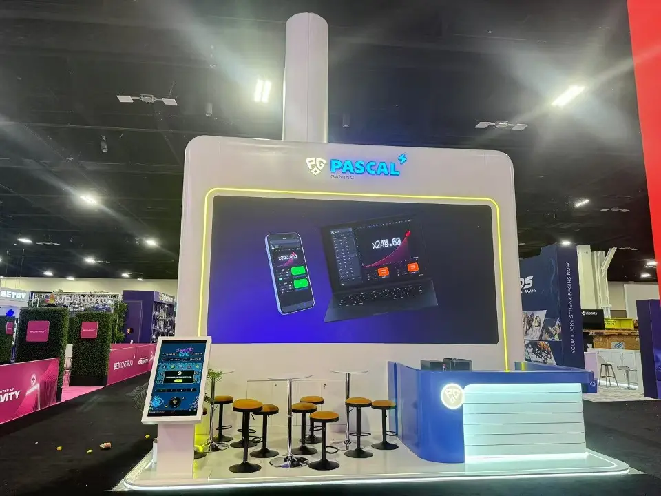 Screen with mobile game graphics above yellow stools and a tablet kiosk