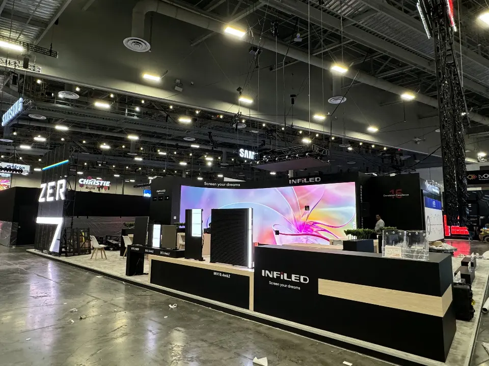 Finished INFiLED booth with long black and white counter facing the curved video screen