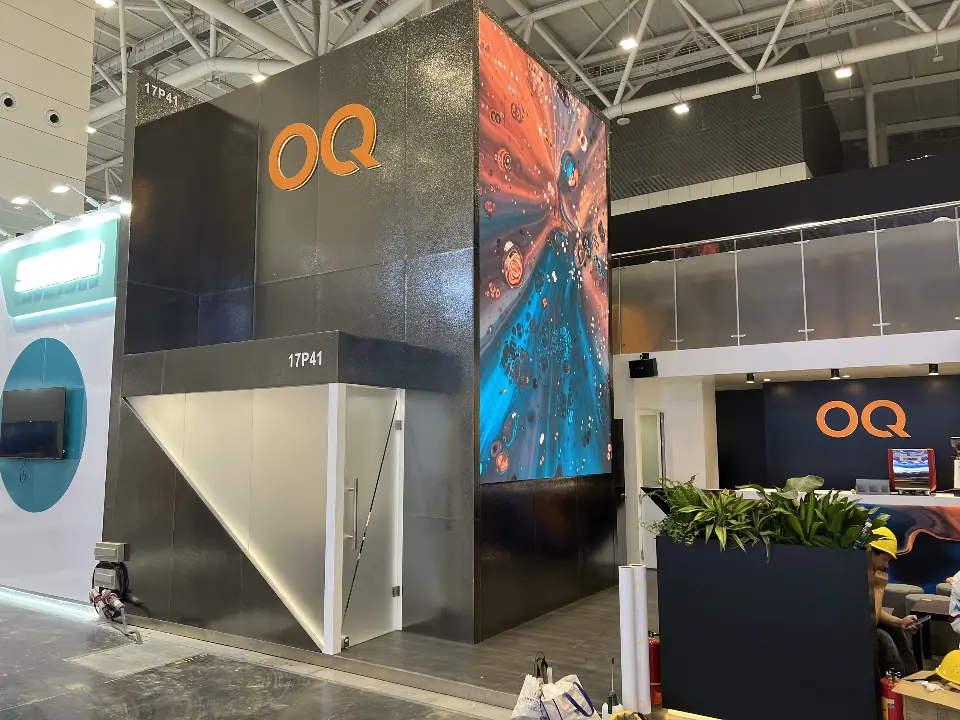 Black OQ tower with orange logo, white angled base and planters