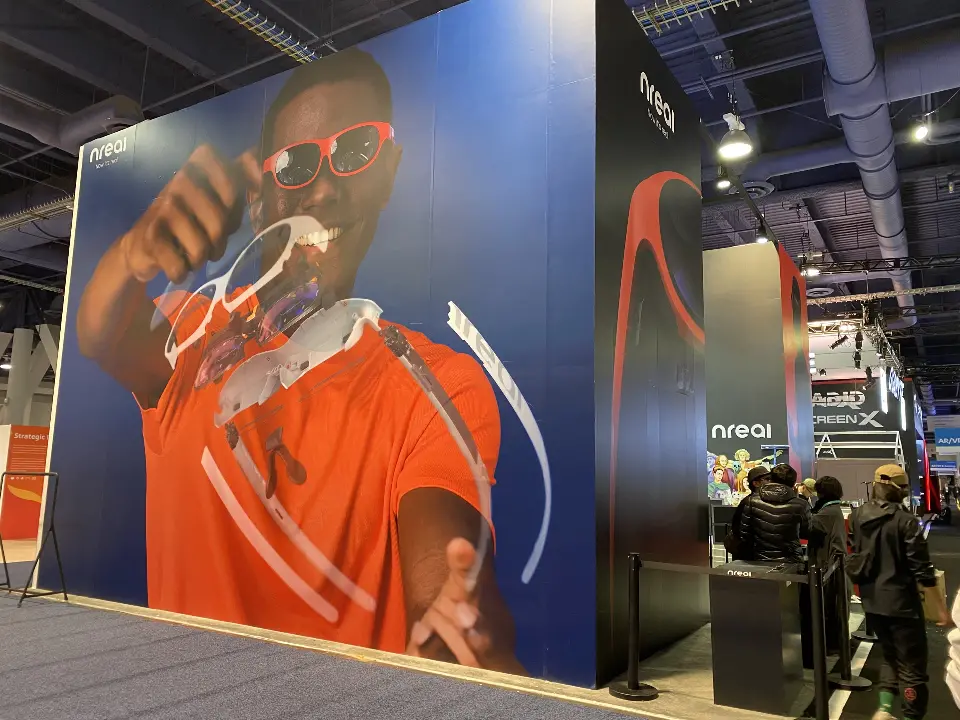 Large photo graphic of a man wearing nreal glasses on a tall booth wall