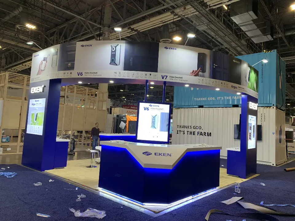 Wide front view of the navy EKEN booth with blue-lit counter and screen towers
