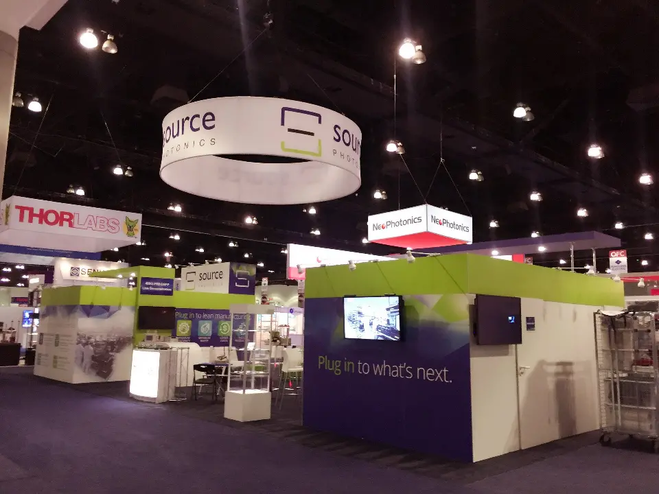 Wider hall view of the white ring sign and purple walls with two screens