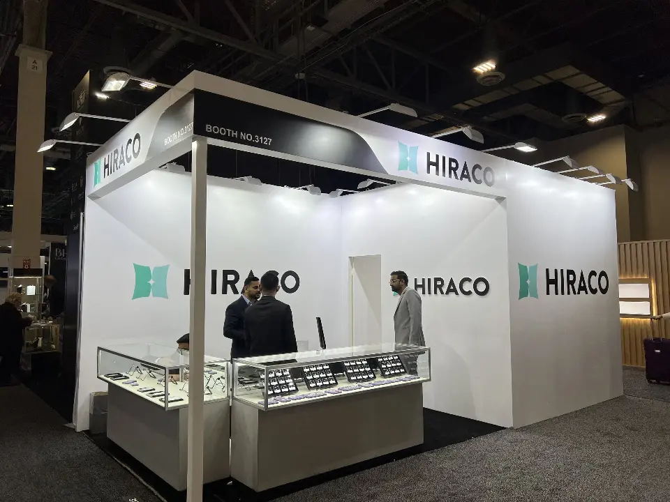 Open front of HIRACO booth 3127 with curved black fascia, white walls and two glass showcases
