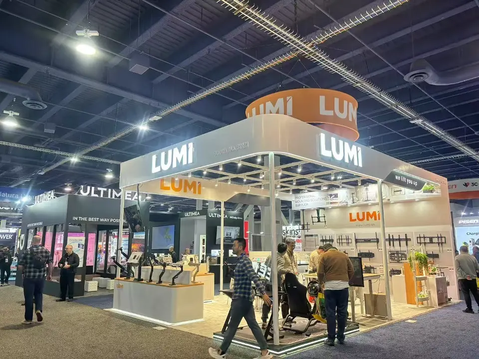 LUMI booth corner with lit orange header, white frame and visitors along the aisle