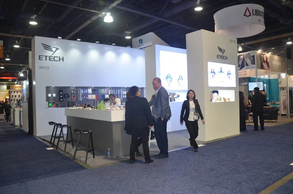 Visitors standing at the grey counter during show hours beside a backlit wall graphic