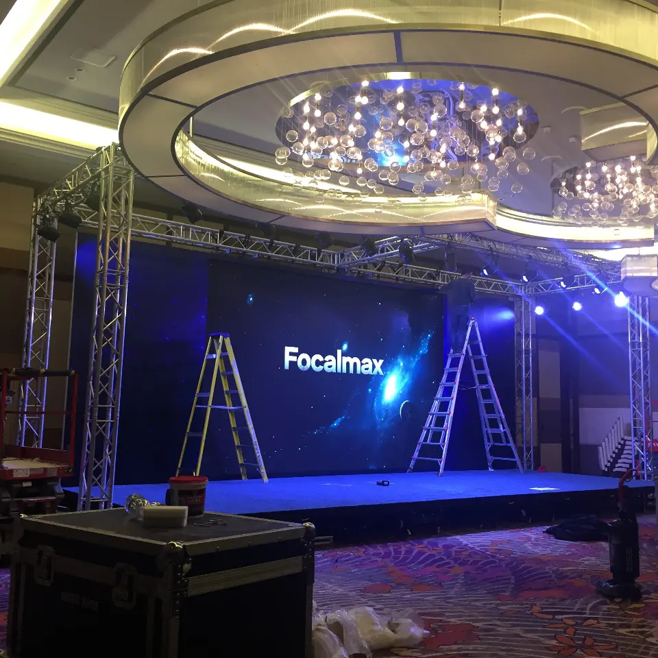 Ballroom stage under a large chandelier with a Focalmax video screen and truss frame