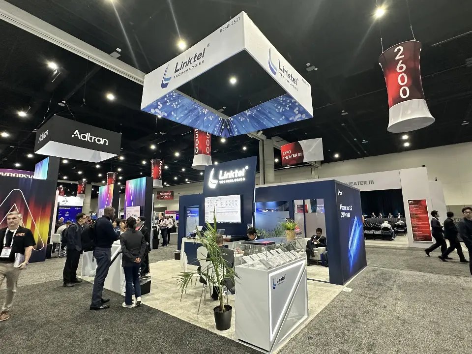 Wider view of the Linktel booth showing the glass meeting room and square sign overhead
