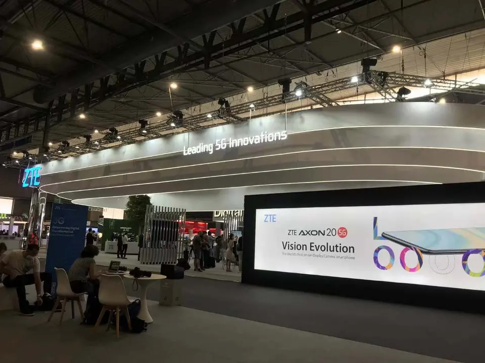 Meeting tables under the canopy facing a large screen with phone graphics