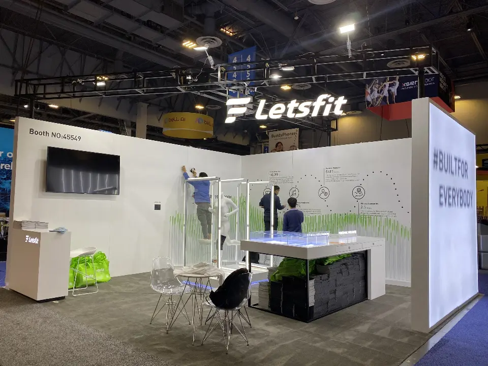 Finished booth with the Letsfit logo wall, wall screen, display counter and caf&eacute; chairs