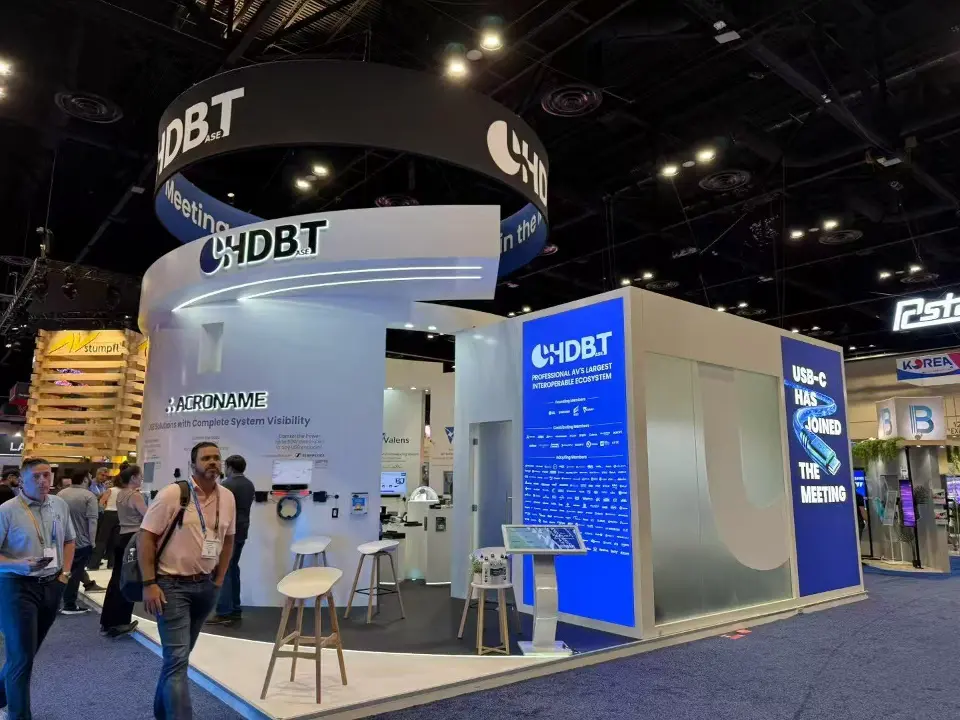 Booth corner with a blue display room beside the white curved HDBT structure