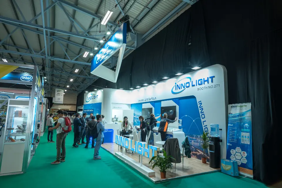 Long aisle view of the InnoLight booth with visitors and a roll-up banner