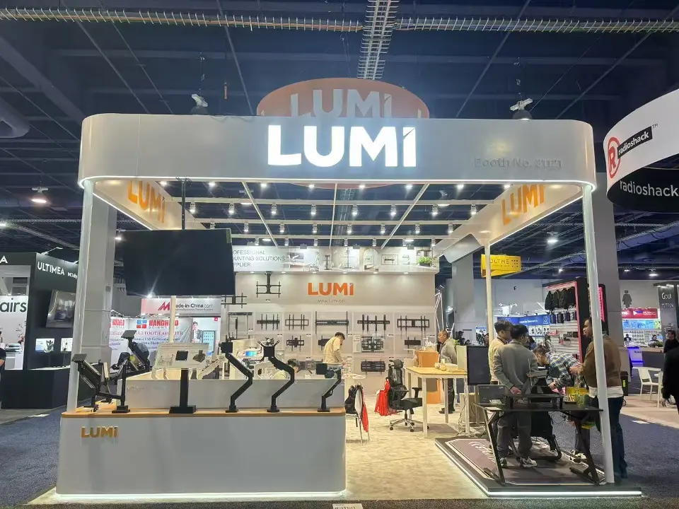 Straight-on front view of the Lumi booth with lit Lumi header and monitor-arm display counter