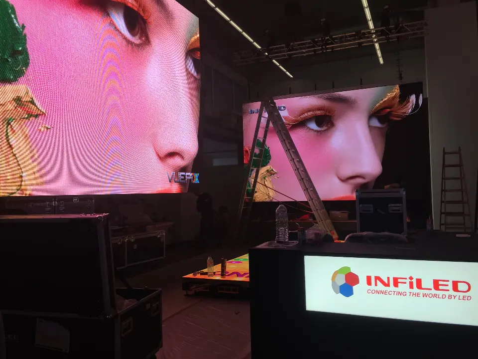 Two video screens with bright imagery behind the lit INFiLED counter