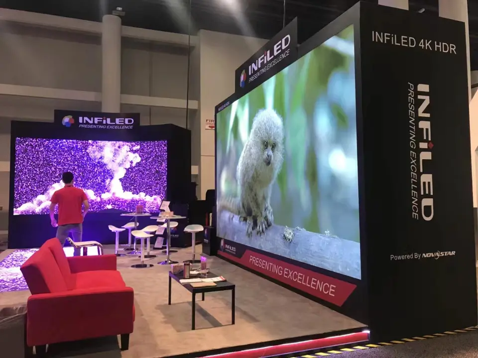 Red sofa and white stools facing two large video screens in the black booth