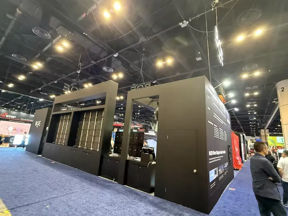 Black side of the BOE booth with framed display niches, a service desk opening and hanging logo