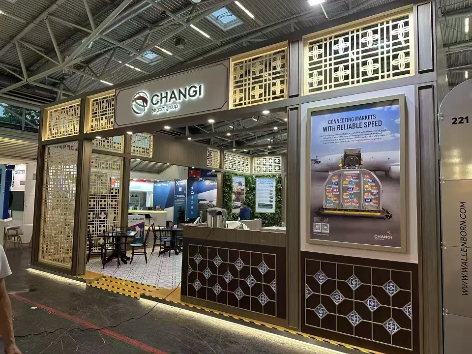 Front of the Changi stand with lattice panels, logo sign and a framed poster