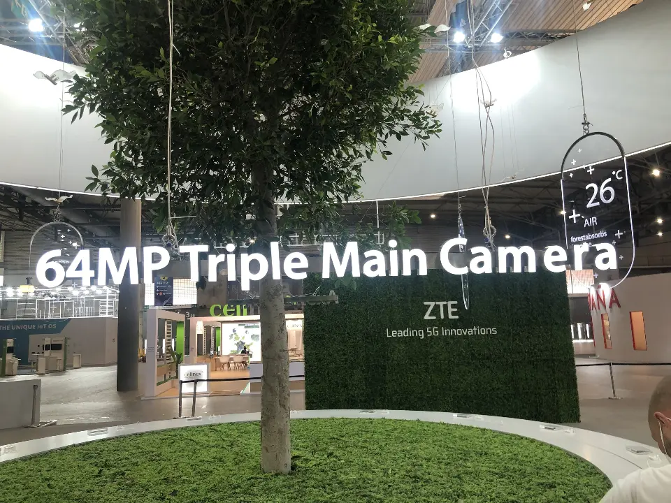 Tree in a grass bed under the 64MP Triple Main Camera sign