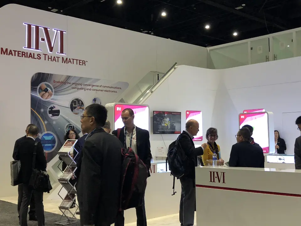 Attendees at the white counter under the II-VI logo and tagline