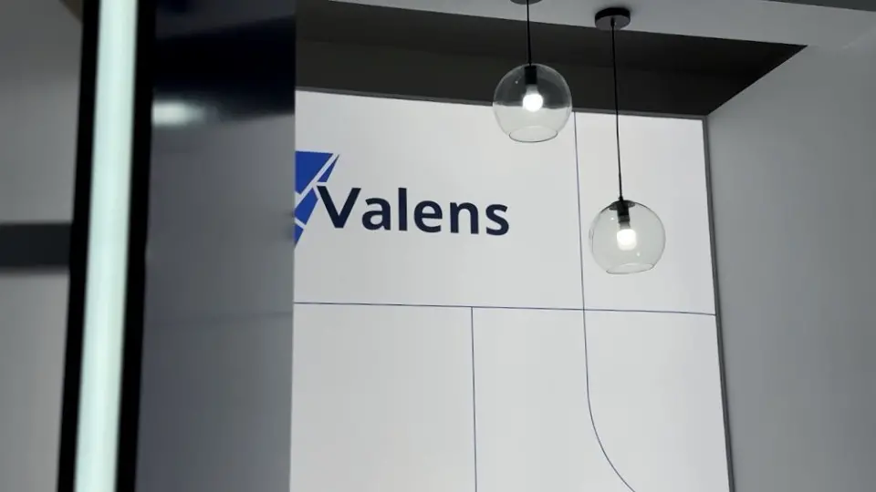 Valens logo on a white wall with two hanging pendant lamps