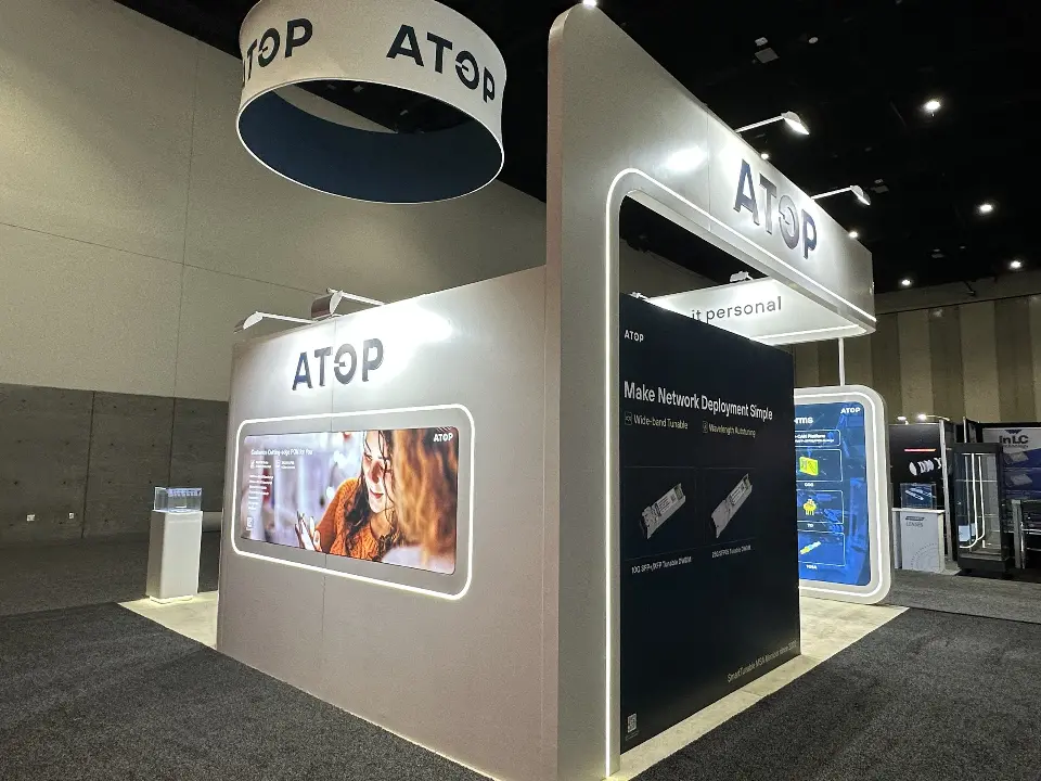 Back side of the ATOP booth with a large backlit graphic and dark product panel