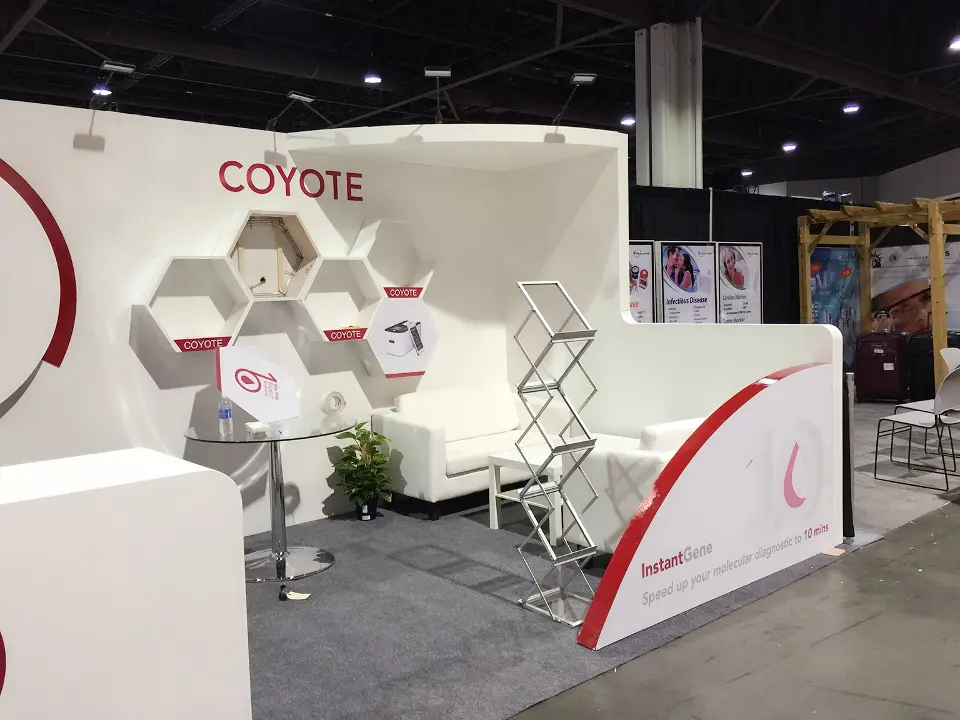 COYOTE white curved wall with hexagon shelving, brochure rack and red swoosh graphic